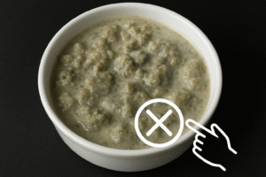 A small amount of evaporated milk showing signs of spoilage (lumps, discoloration) with a visual warning sign or a hand pointing to the fault.