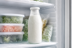 A frozen bottle of skim milk stored safely inside a clean residential freezer.