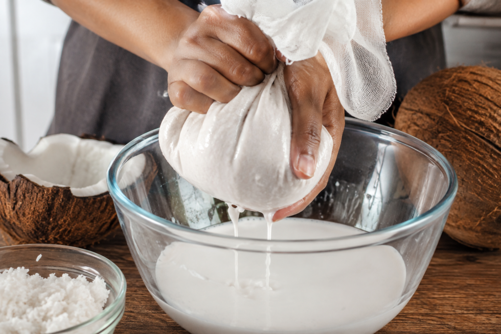 Squeezing grated coconut through a cloth bag to extract fresh coconut milk.