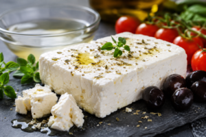 Authentic white block of Greek feta cheese on a slate board with olive oil and oregano